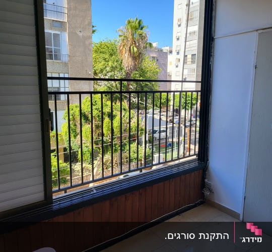 מסגרת חלון עם תריסים ומעקה ברזל